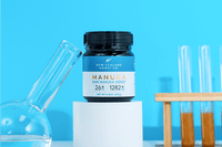 Geöffnetes Glas Manuka Honig UMF™ 26+ MGO 1282+ mit Holzlöffel auf neutralem Hintergrund