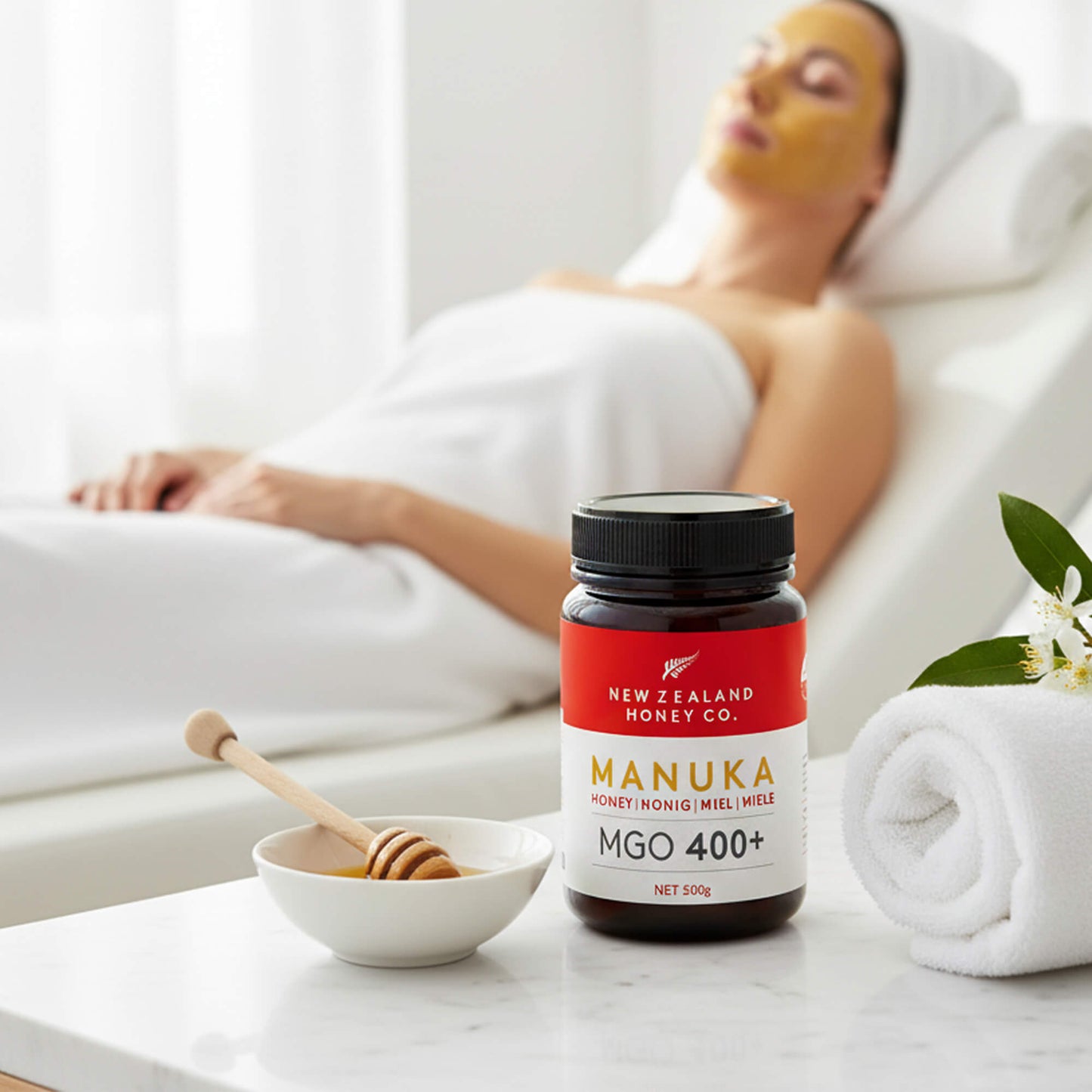 Frau mit Honig-Gesichtsmaske bei Wellness-Anwendung – Manuka Honig MGO 400+ im Vordergrund